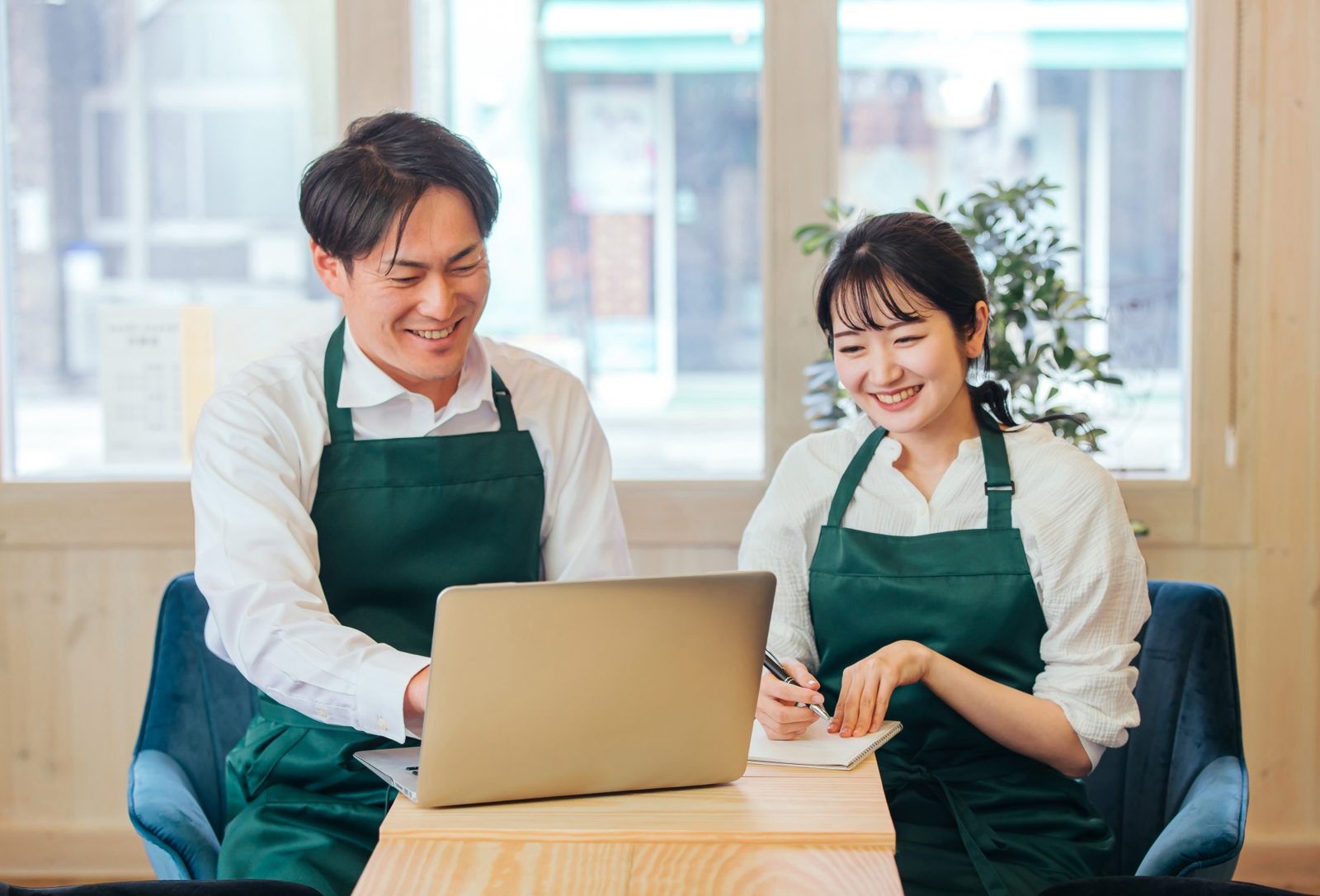 ノートパソコンを見ながら笑顔で話すお店の二人